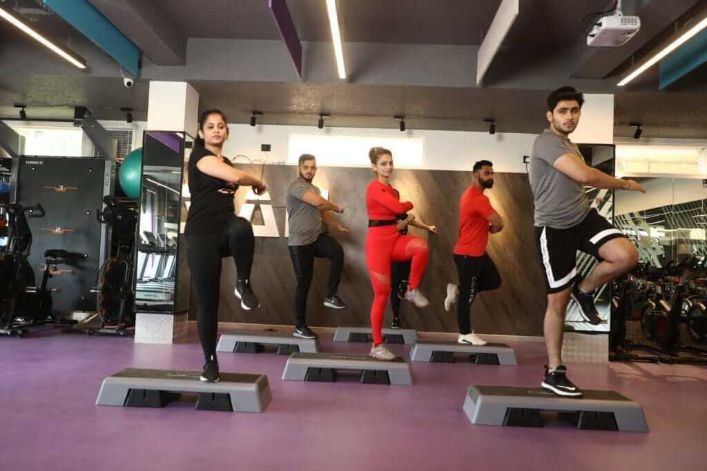 Coach-led group training in a modern gym — step class with focused, energetic participants